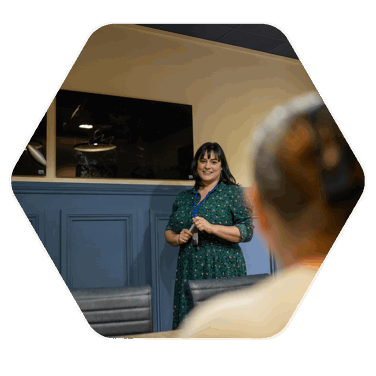 A woman addressing a room in a meeting room, with screens behind her