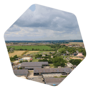 A drone shot of an industrial area with field behind said site 