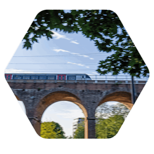 A side angle of a viaduct with a train travelling along the top of the viaduct at speed causing the foreground to blur slightly