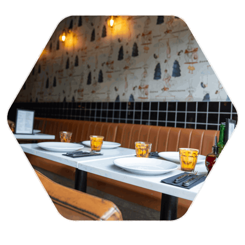 Restaurant tables with plates, place settings and orange glasses laid atop the tables