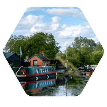 A scenic image of a canal boat docked in a loch, next to a small building onshore 